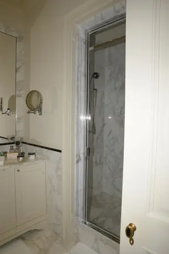 Bagno: EFTA00000240 - Bathroom featuring marble walls a glass shower enclosure a vanity with toil