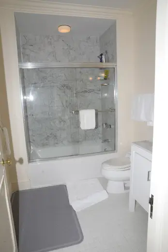 Bagno: EFTA00000562 - Clean bathroom featuring a marble-tiled shower white toilet and tiled floor
