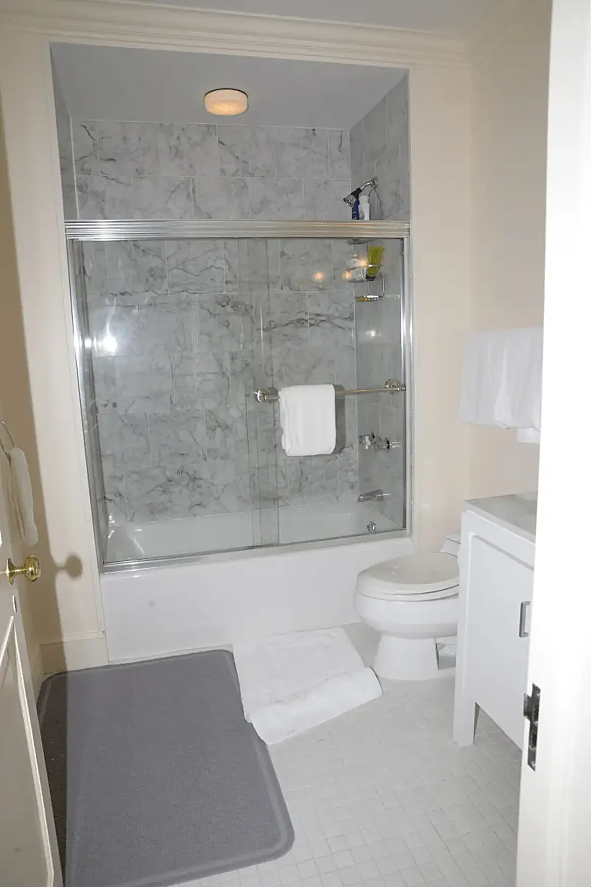Baño: EFTA00000562 - Clean bathroom featuring a marble-tiled shower white toilet and tiled floor