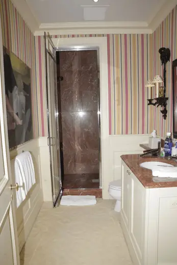 Bagno: EFTA00000596 - Bathroom with striped walls a marble shower white cabinets and a patterned 