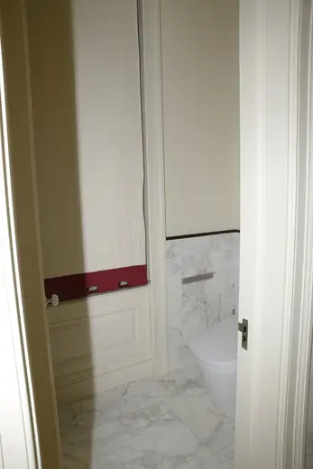 Bagno: EFTA00000604 - Bathroom with white marble flooring a modern toilet and a red trim on the w