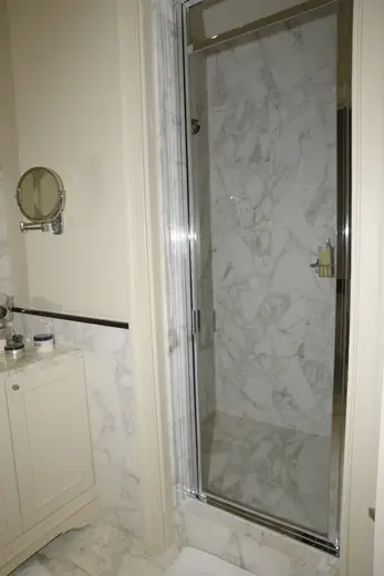 Bagno: EFTA00000605 - Luxurious bathroom featuring marble walls a glass shower door and a vanity 