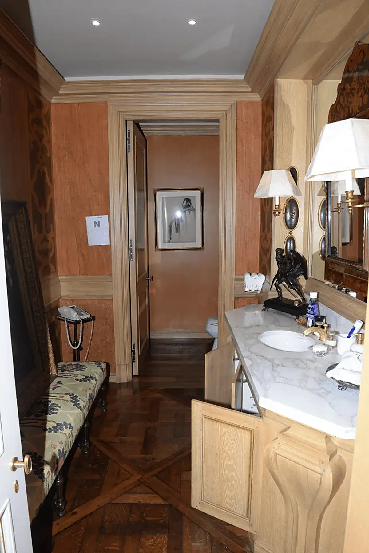 Bathroom: EFTA00001027 - Luxurious bathroom with wooden floors ornate wall paneling a marble counter