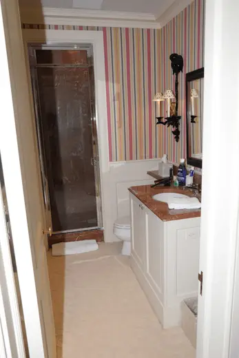 Bagno: EFTA00001111 - Bathroom with striped wallpaper a marble countertop a glass shower and whit