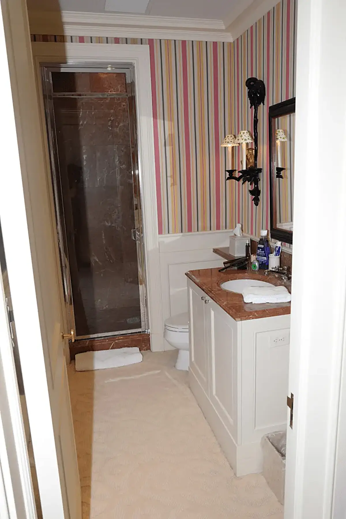 Bathroom: EFTA00001111 - Bathroom with striped wallpaper a marble countertop a glass shower and whit