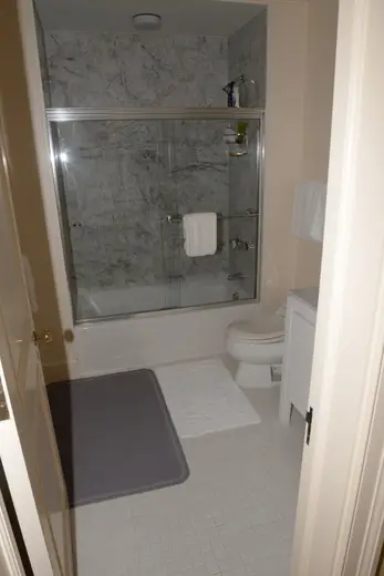 Bagno: EFTA00001163 - Small bathroom featuring a shower with marble tiles white fixtures and a gr