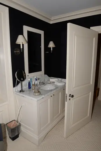 Bagno: EFTA00001179 - White bathroom vanity with marble countertop black walls and a partially op
