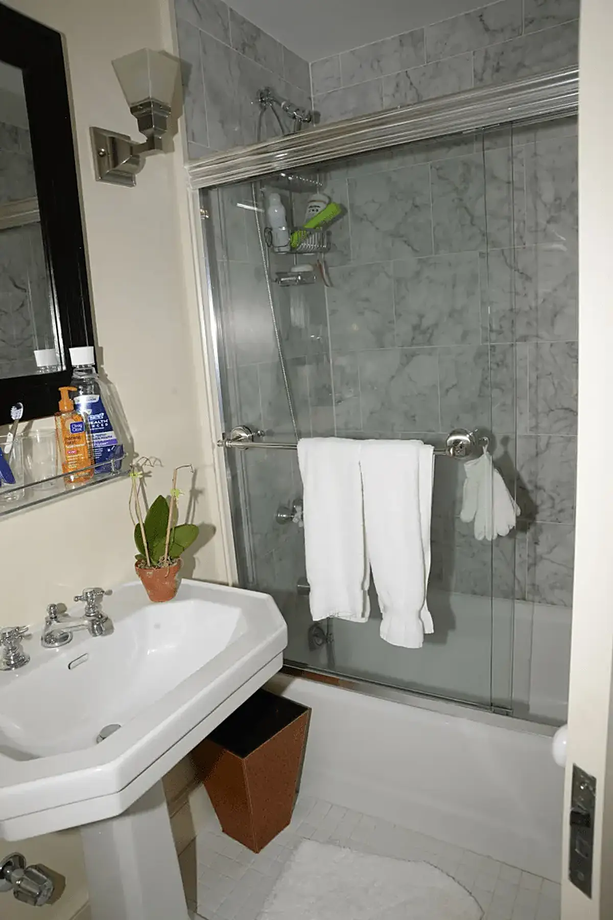 Bathroom: EFTA00000296 - Bathroom with a white pedestal sink marble-tiled walls a glass shower enclo