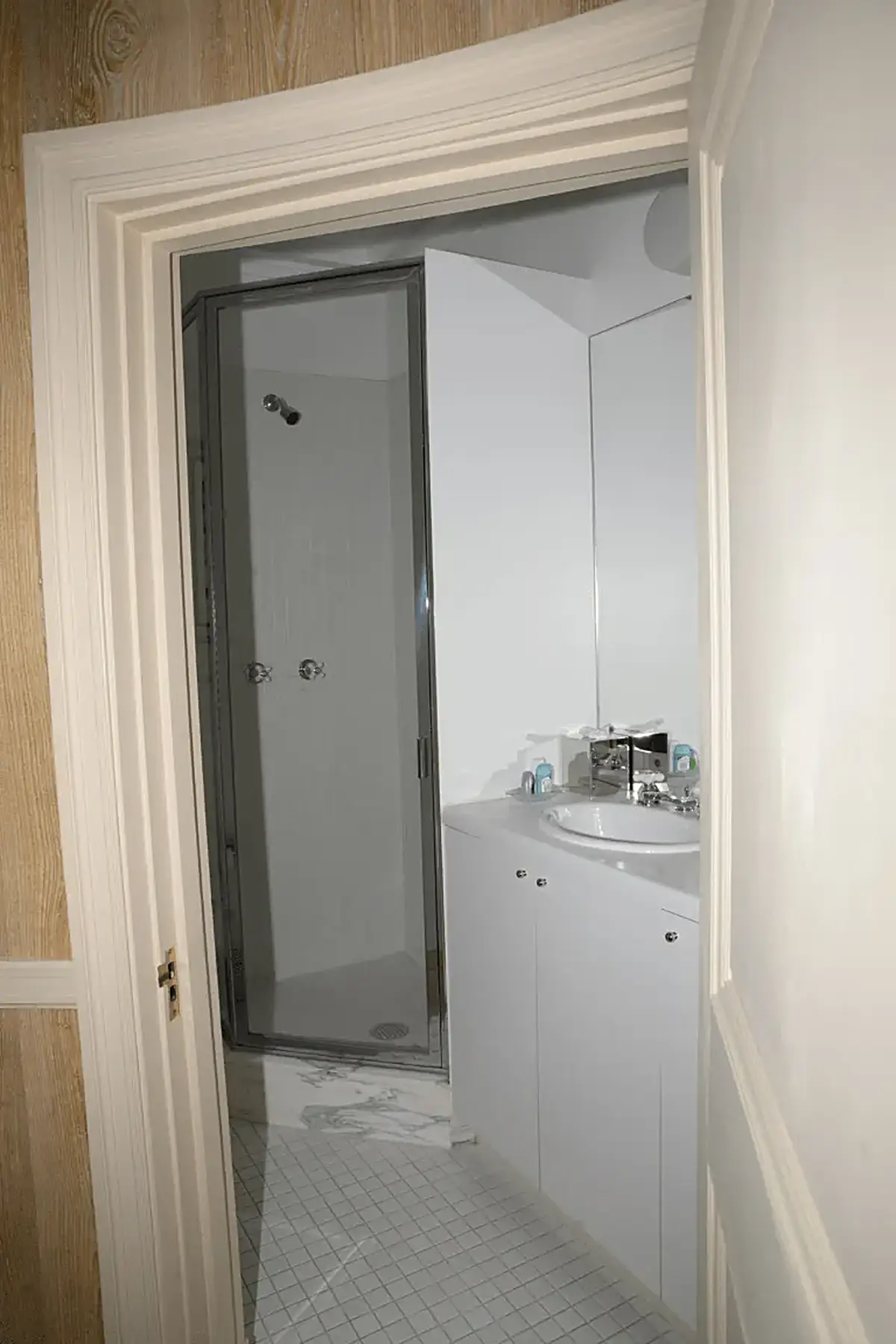 Bathroom: EFTA00000809 - White bathroom with glass shower door sink and marble floor tiles viewed th