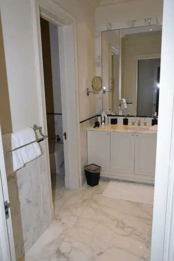 Bagno: EFTA00001116 - Modern bathroom featuring marble flooring white cabinets a large mirror and