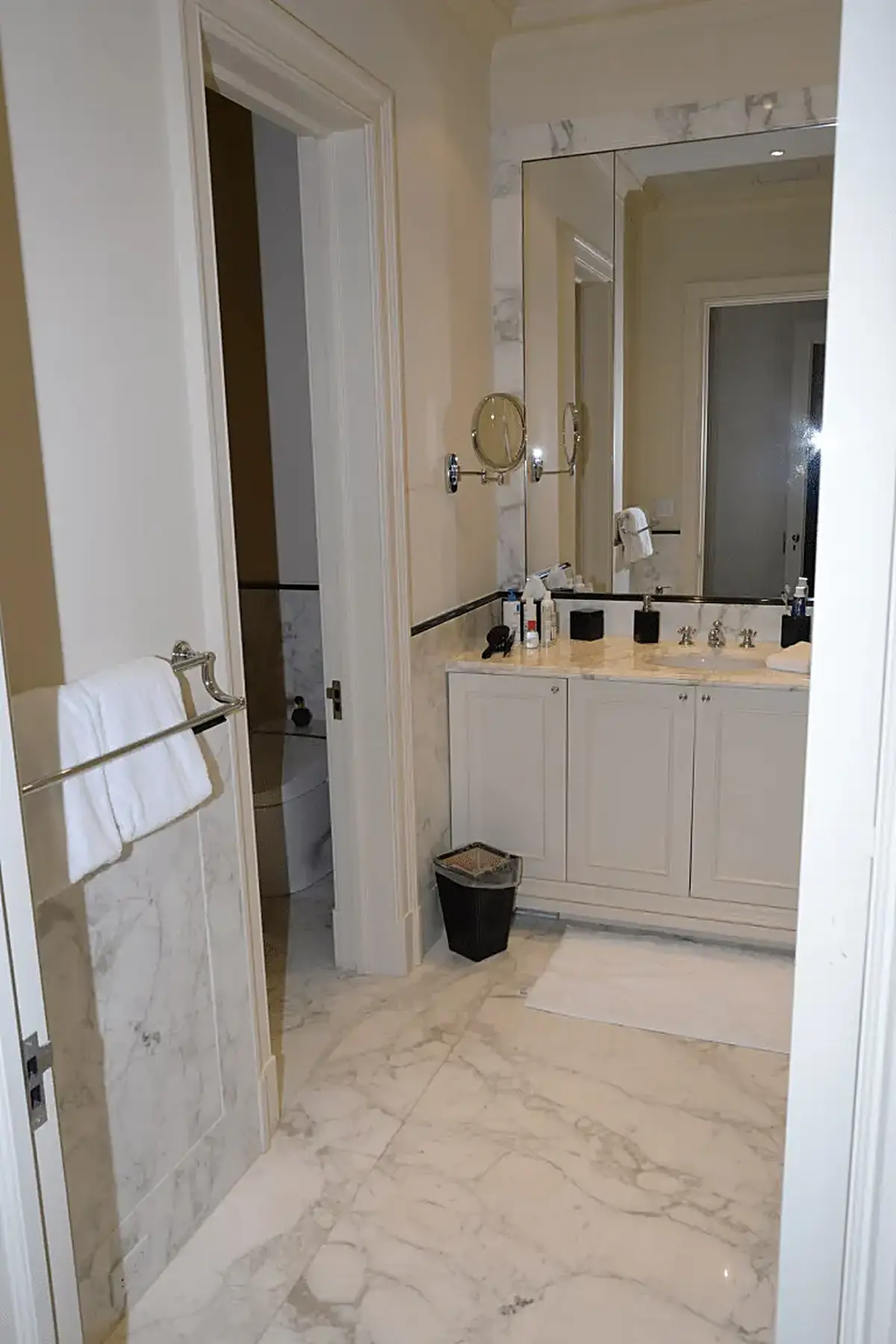 Bathroom: EFTA00001116 - Modern bathroom featuring marble flooring white cabinets a large mirror and