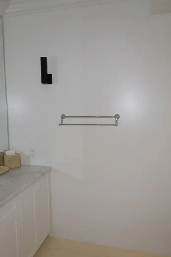 Bagno: EFTA00001602 - White bathroom with marble countertop silver towel bar and black wall sconc