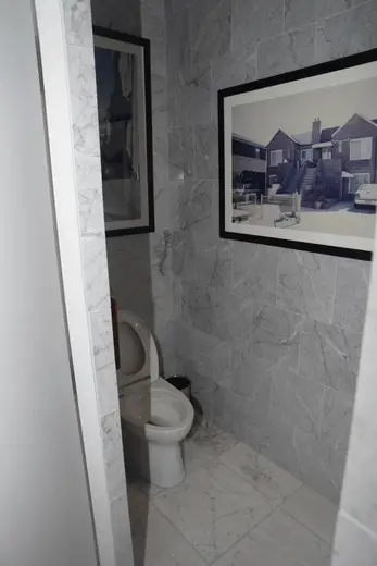 Bagno: EFTA00002891-Pool-House - Small bathroom with gray marble walls a white toilet and framed 