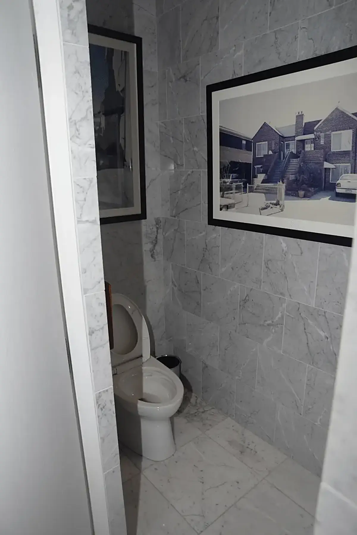 Bathroom: EFTA00002891-Pool-House - Small bathroom with gray marble walls a white toilet and framed 