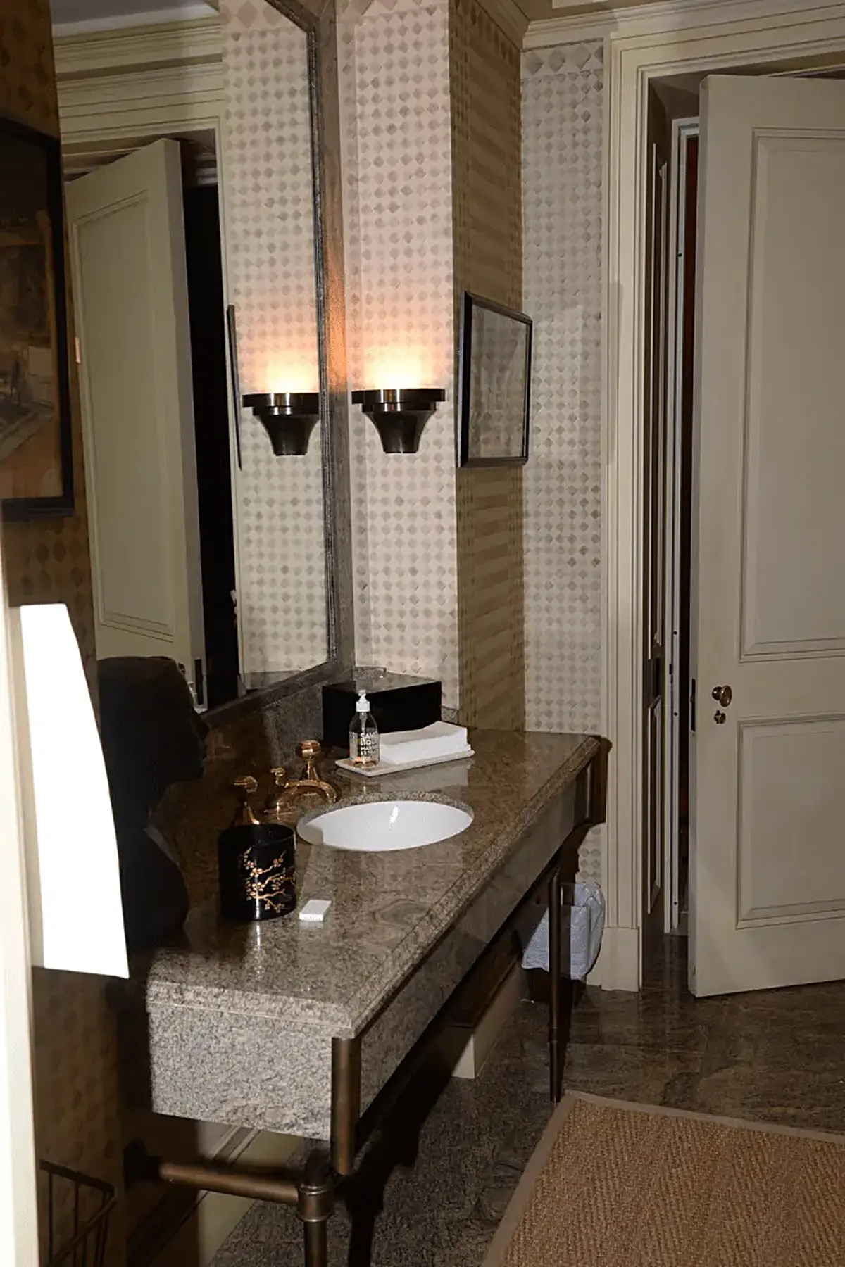Bathroom: EFTA00000908 - Bathroom with a granite countertop white sink gold fixtures patterned wallp
