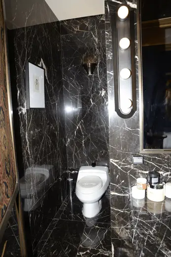 Bagno: EFTA00000172 - Luxurious bathroom with black marble walls a white toilet and a mirror illu