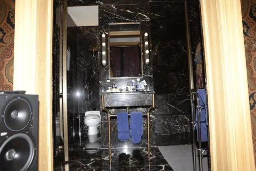 Bagno: EFTA00000173 - Luxurious bathroom with black marble walls a gold-framed mirror with lights