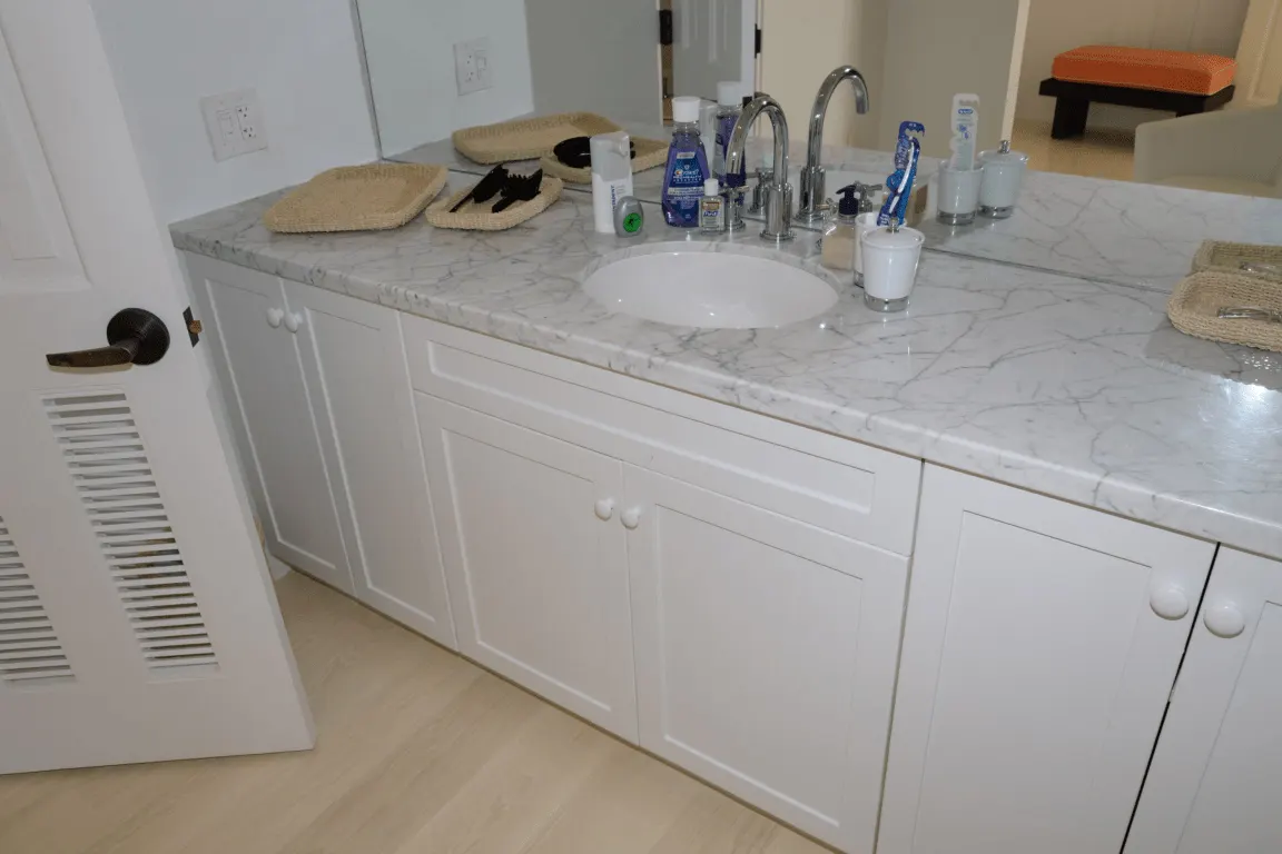 Bathroom: EFTA00001599 - White marble bathroom counter with sink faucet and toiletries A white door 