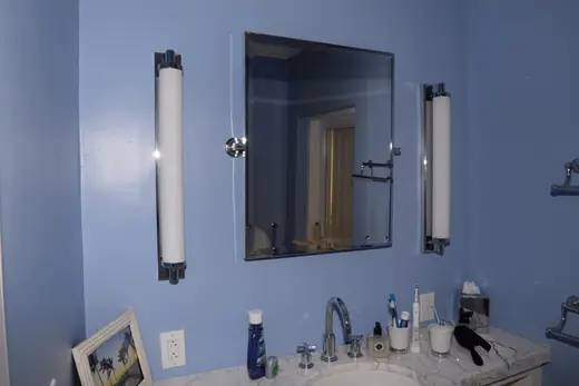 Bagno: EFTA00001792 - Bathroom with blue walls a marble countertop and a mirror flanked by two wh