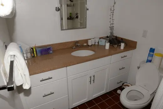 Bagno: EFTA00001701 - White bathroom with tan countertop sink mirror and toilet A towel hangs on 