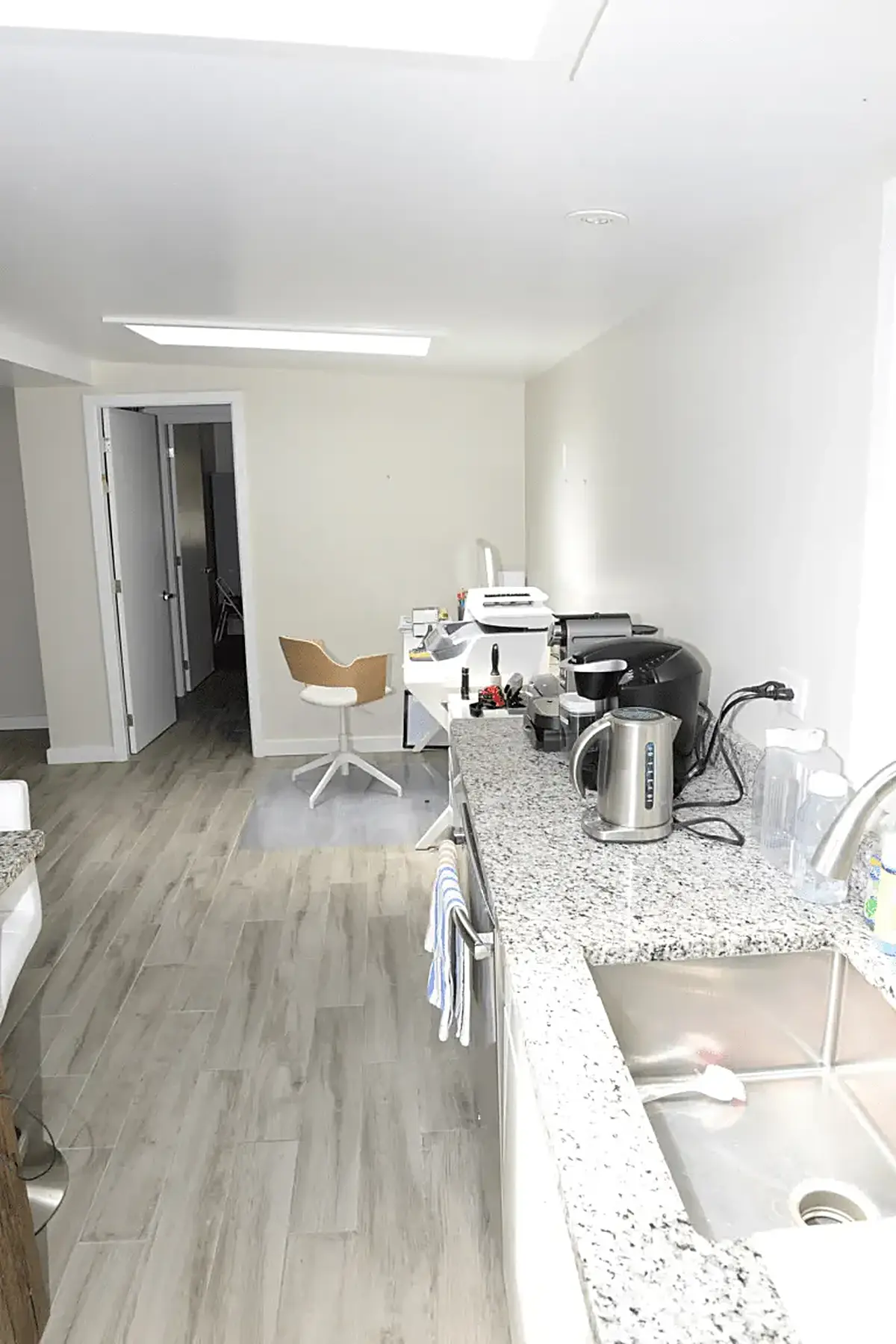 Kitchen: EFTA00002082 - Modern kitchen with light wood floors white walls and a granite countertop