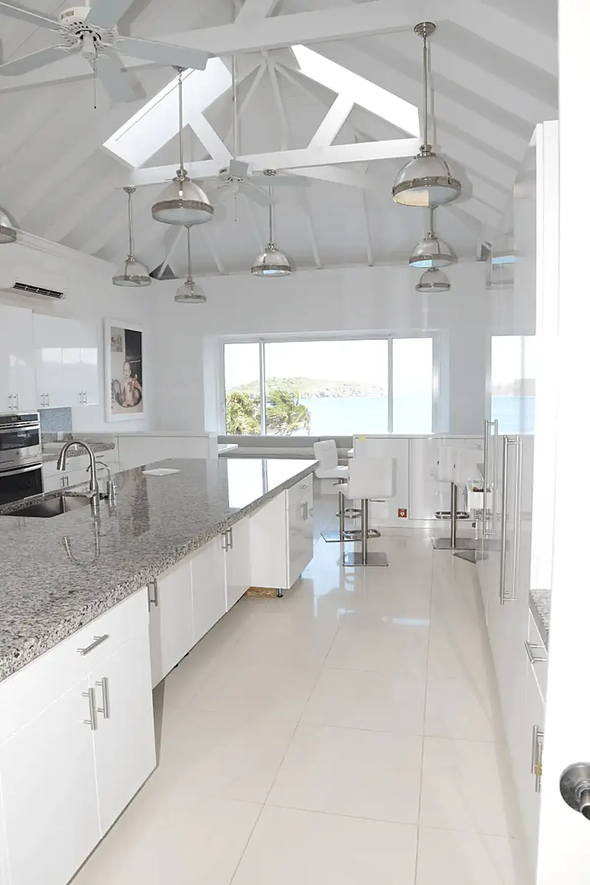 Cucina: EFTA00001524 - Bright white kitchen with granite countertops skylights and ocean view thro
