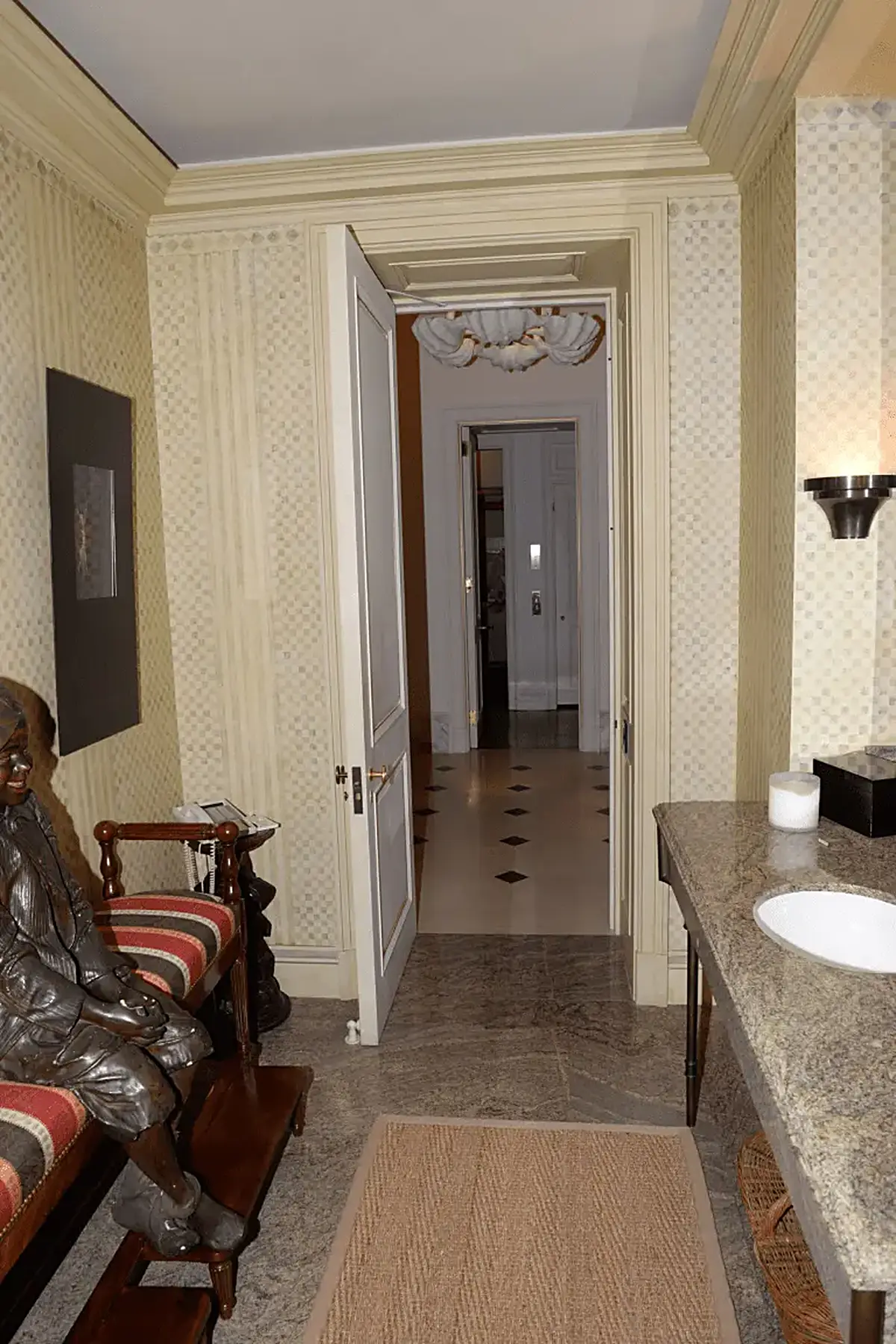 Kitchen: EFTA00000937 - Hallway with patterned wallpaper a marble countertop and a bronze statue le