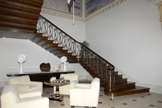 Staircase: EFTA00000053 - Grand wooden staircase with intricate iron railings ascends flanked by whit